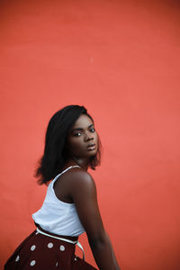 African american fashion model profile photo of fashion model, sitting down, orange color background
