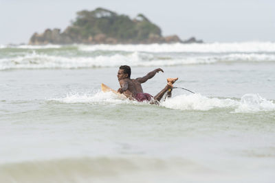 Shirtless man surfing in sea against sky