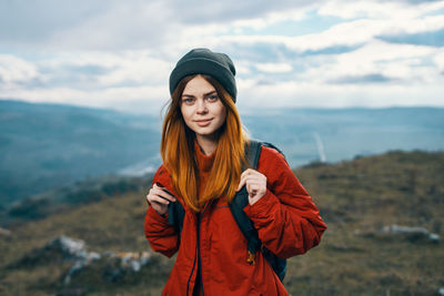 Portrait of beautiful young woman standing against sky during winter