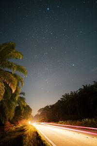 Road amidst trees against sky at night