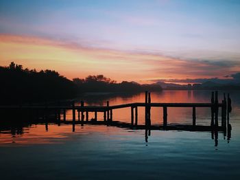 Silhouette pier on lake against sky during sunset