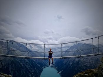 Man standing on bridge against sky