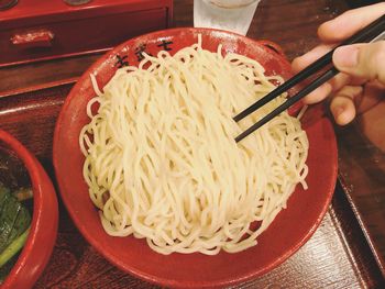 Close-up of hand holding noodles in bowl