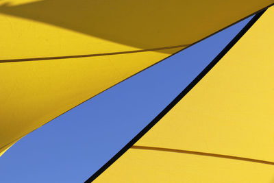 Low angle view of yellow umbrella against clear blue sky