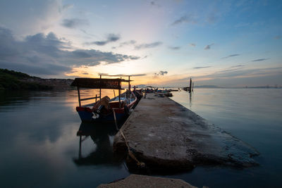 Boat moored in sea against sky during sunset