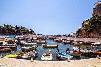 Boats moored on beach against clear blue sky