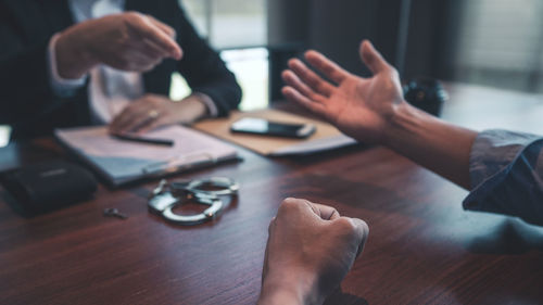 Midsection of man pointing at businessman sitting at table