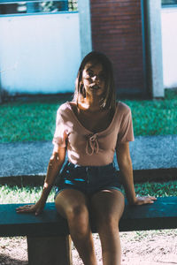 Portrait of teenage girl sitting on bench at park