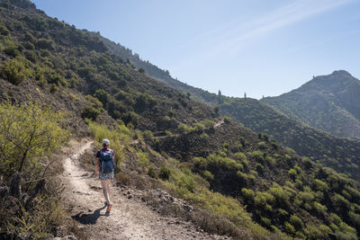 Rear view of woman hiking on mountain trail