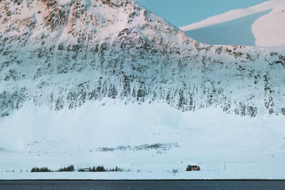 Scenic view of sea by snowcapped mountain against sky