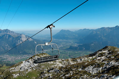 Overhead cable car over mountains against sky