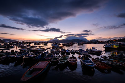 Boats moored on sea against sky during sunset