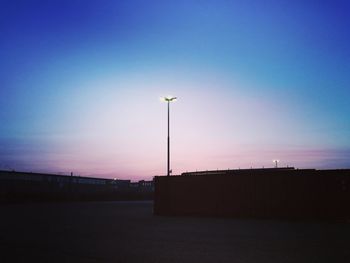 Illuminated street light against clear blue sky at night