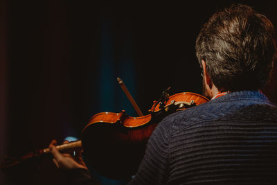 Rear view of man playing violin