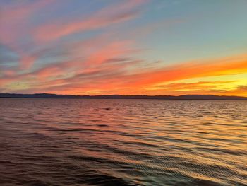 Scenic view of sea against dramatic sky during sunset