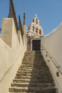 Low angle view of steps amidst buildings against clear blue sky