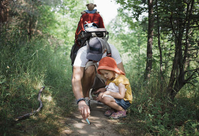 Father with daughter looking on field amidst trees in forest