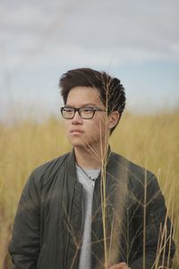 Young man standing on field against sky