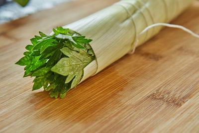 Ready-made bouquet of greens lies on a wooden board in the kitchen, for dressing dish