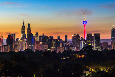 Illuminated buildings in city against sky during sunset