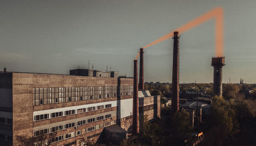 Smoke emitting from factory against sky