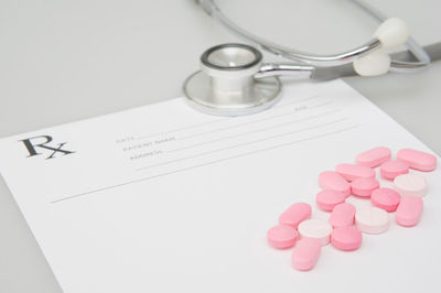 High angle view of pills over paper by stethoscope