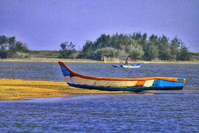 Boat moored on sea shore against sky