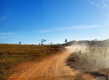 Dirt road amidst landscape against sky