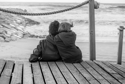 Rear view of couple sitting on beach 