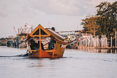 Traditional boat in river by building against sky