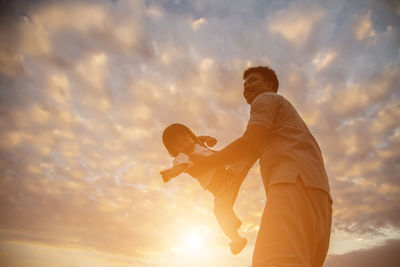 Low angle view of man standing against sky during sunset