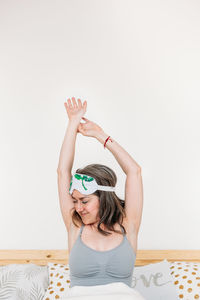 Portrait of young woman sitting against wall