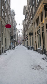 Snow covered street amidst buildings in city