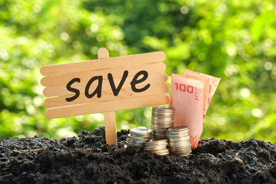 Close-up of a signboard and currency on field