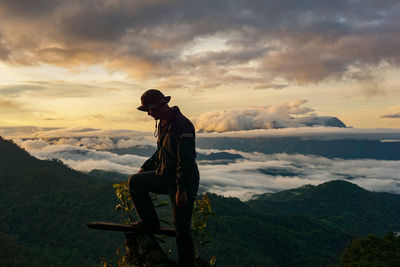 Side view of man standing on mountain against sky during sunset