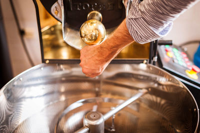 Cropped hand of barista preparing coffee in machinery at cafe