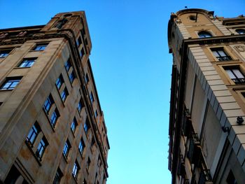 Low angle view of buildings against clear blue sky