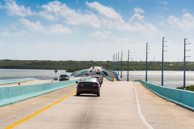 Cars on road by sea against sky