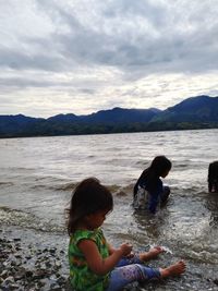 Children on beach against sky