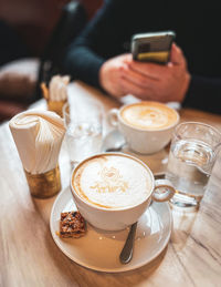 Cropped hand of woman using mobile phone on table