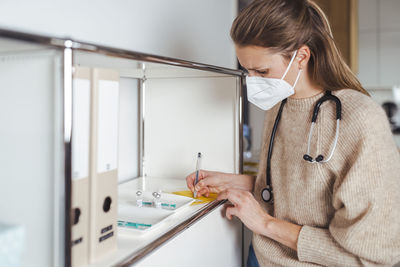 Doctor in protective face mask signing immunization certificate at center