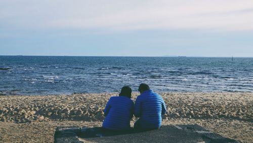 Rear view of couple sitting at beach