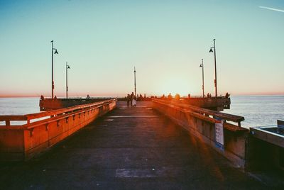 Pier on sea against clear sky during sunset