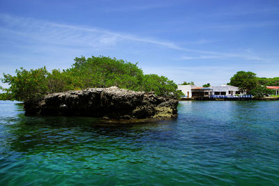 Scenic view of rock formation in sea against blue sky