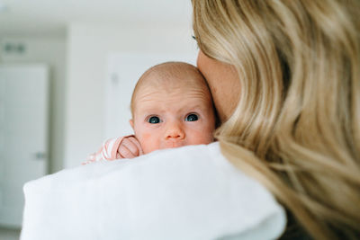 Over the shoulder view of a newborn baby girl being held by her mom