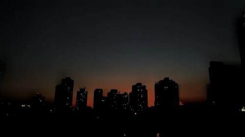 Silhouette buildings against sky at night