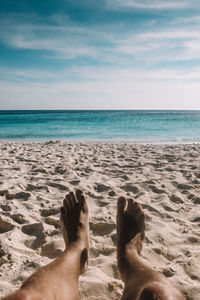 Low section of man on sand at beach against sky