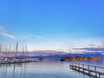 Sailboats moored in sea against sky