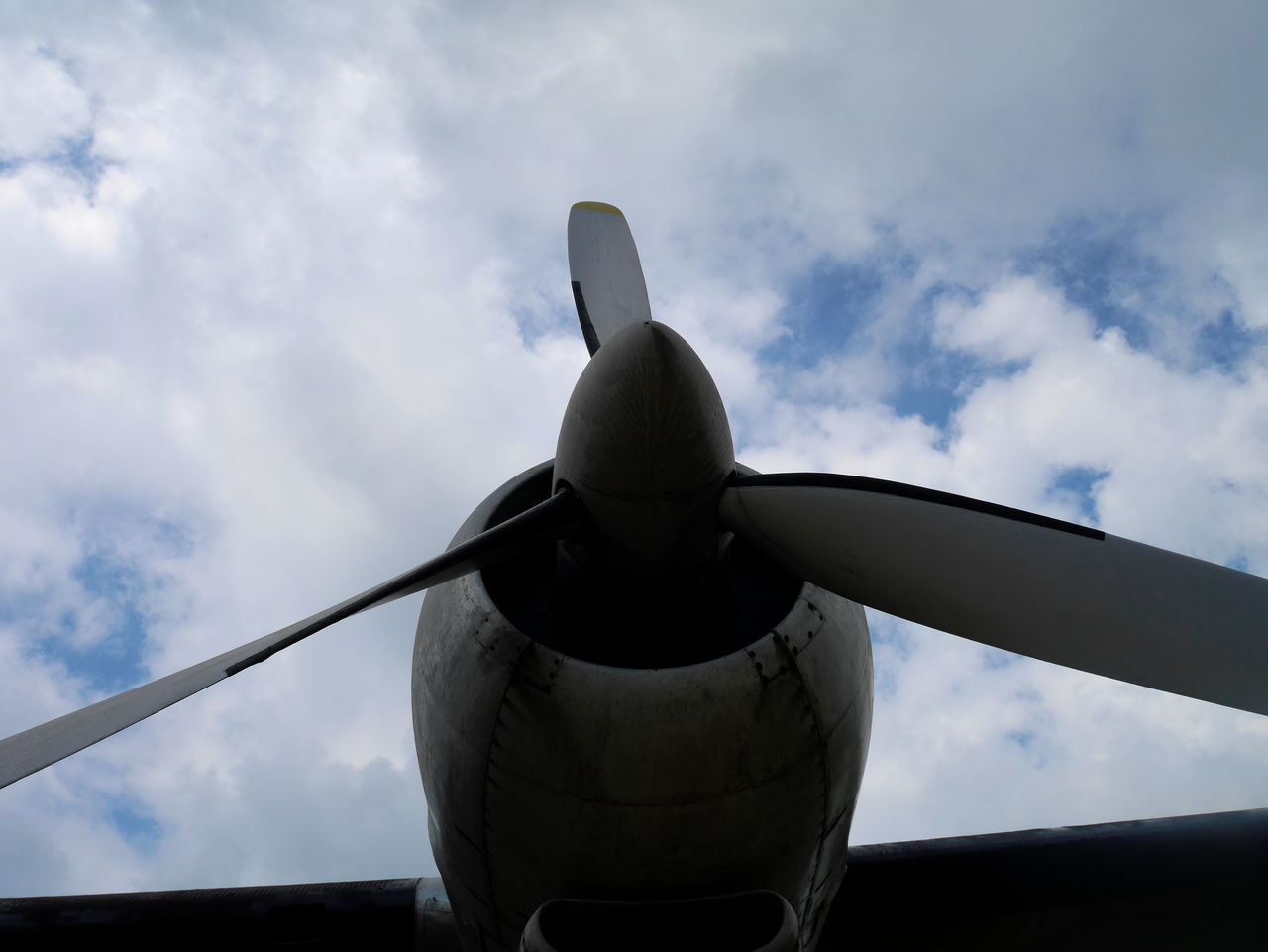 LOW ANGLE VIEW OF AIRPLANE AGAINST CLOUDY SKY