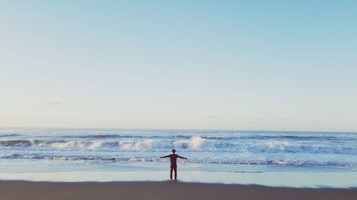 Man standing on beach against clear sky